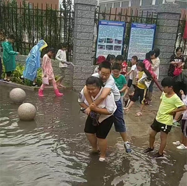 聊城：大雨過后校門口積水，95年女校車管理員背38個孩子上校車