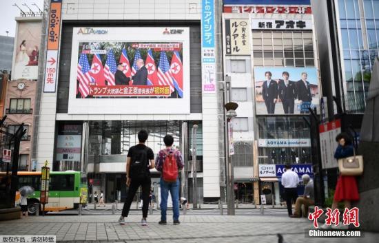 資料圖：2018年6月，在日本東京的一個(gè)廣場，人們通過戶外大屏幕觀看朝美領(lǐng)導(dǎo)人首次會晤的直播畫面。